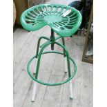 A cast iron adjustable tractor seat on stool base in green