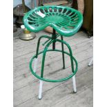 A cast iron adjustable tractor seat on stool base in green