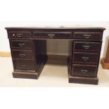 A Victorian ebonised and walnut banded kneehole pedestal desk fitted nine drawers with green