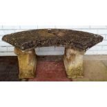 An arc shaped reconstituted stone garden bench on concrete base