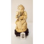 An oriental ivory carving of a sage with a book and a long black beard standing on a black ebonised