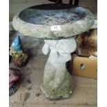 A reconstituted stone garden birdbath with young child face