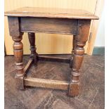 An antique oak joint stool on oak legs with stretchers