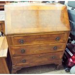 A figured walnut bureau with three drawers under standing on cabriole feet,