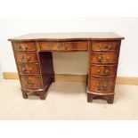 An early reproduction mahogany serpentine front twin pedestal desk fitted nine drawers with green