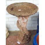 A reconstituted stone garden bird bath approximately 24" high with squirrels climbing the base