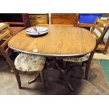 An Ercol medium oak oval extending dining table with fold away leaf together with a pair of