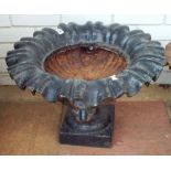 A large black painted, cast iron, urn decorated with lion heads 54 cms diameter,