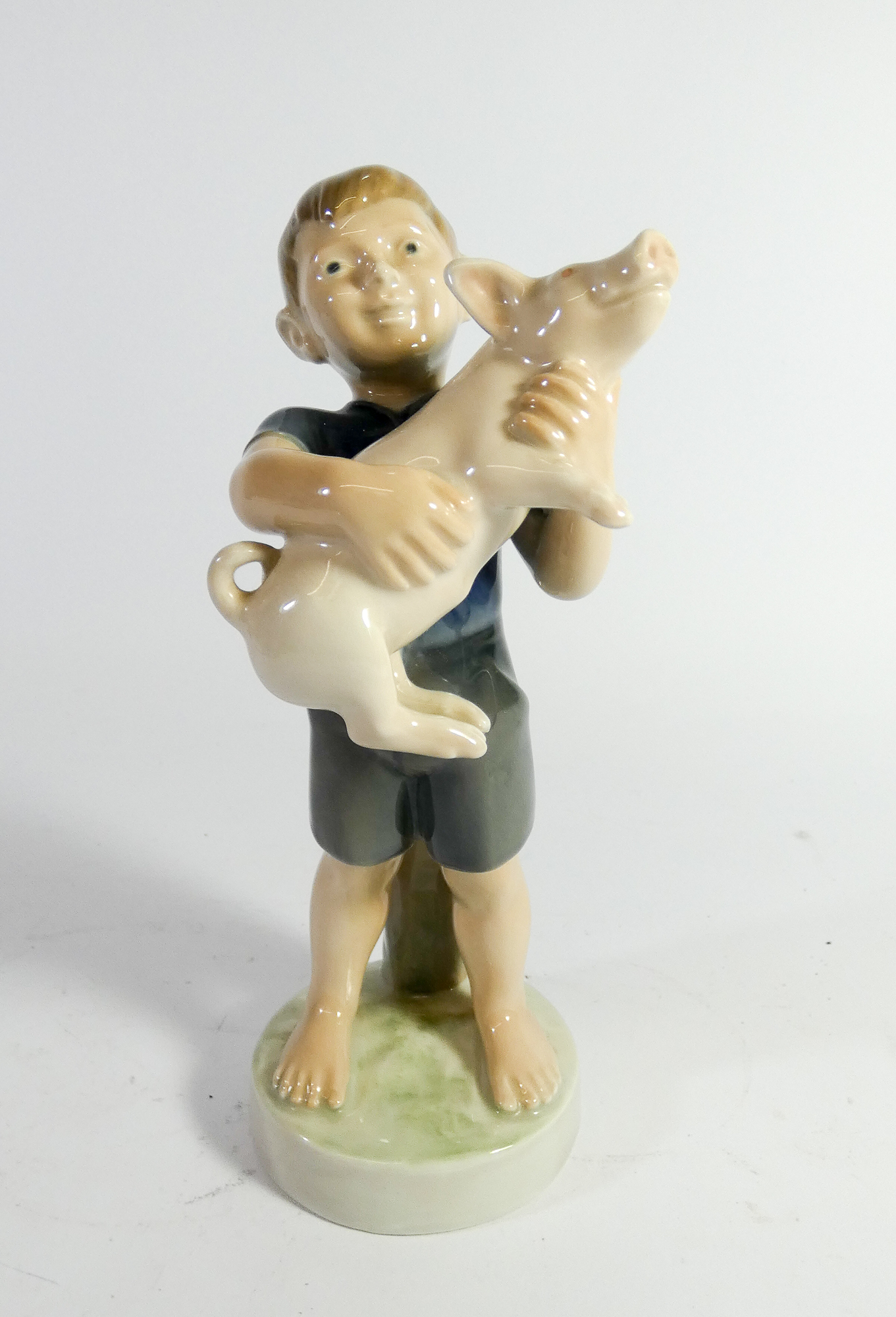 A Royal Copenhagen figure of a boy holding a piglet No.