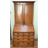 A Georgian golden oak bureau bookcase with double panel doors and interior shelves,