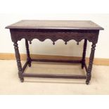 A carved dark oak two tier hall table on turned legs with stretchers,