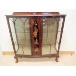 A Mahogany bow fronted glazed china display cabinet with lacquered centre panel standing on claw