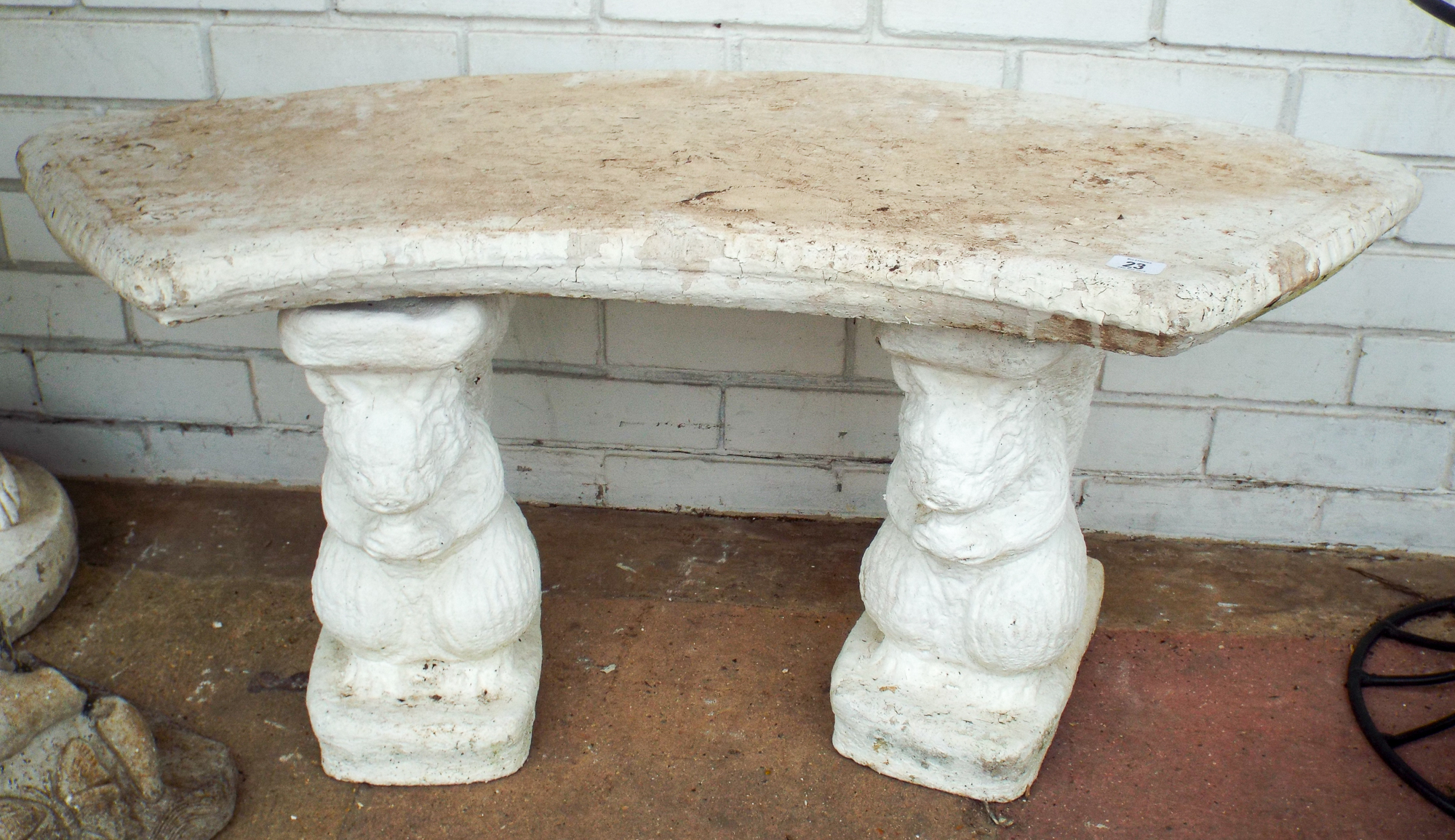 A curved shape reconstituted stone two seater garden bench with squirrel base