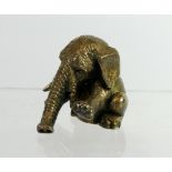 A silver miniature model of a seated baby elephant balancing on his trunk, 92 grams.