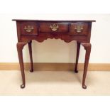 An oak lowboy, fitted with three draws with brass handles, standing on cabriole style legs,