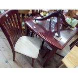 A mahogany extending dining table with fold away leaf and four matching slat back chairs with cream