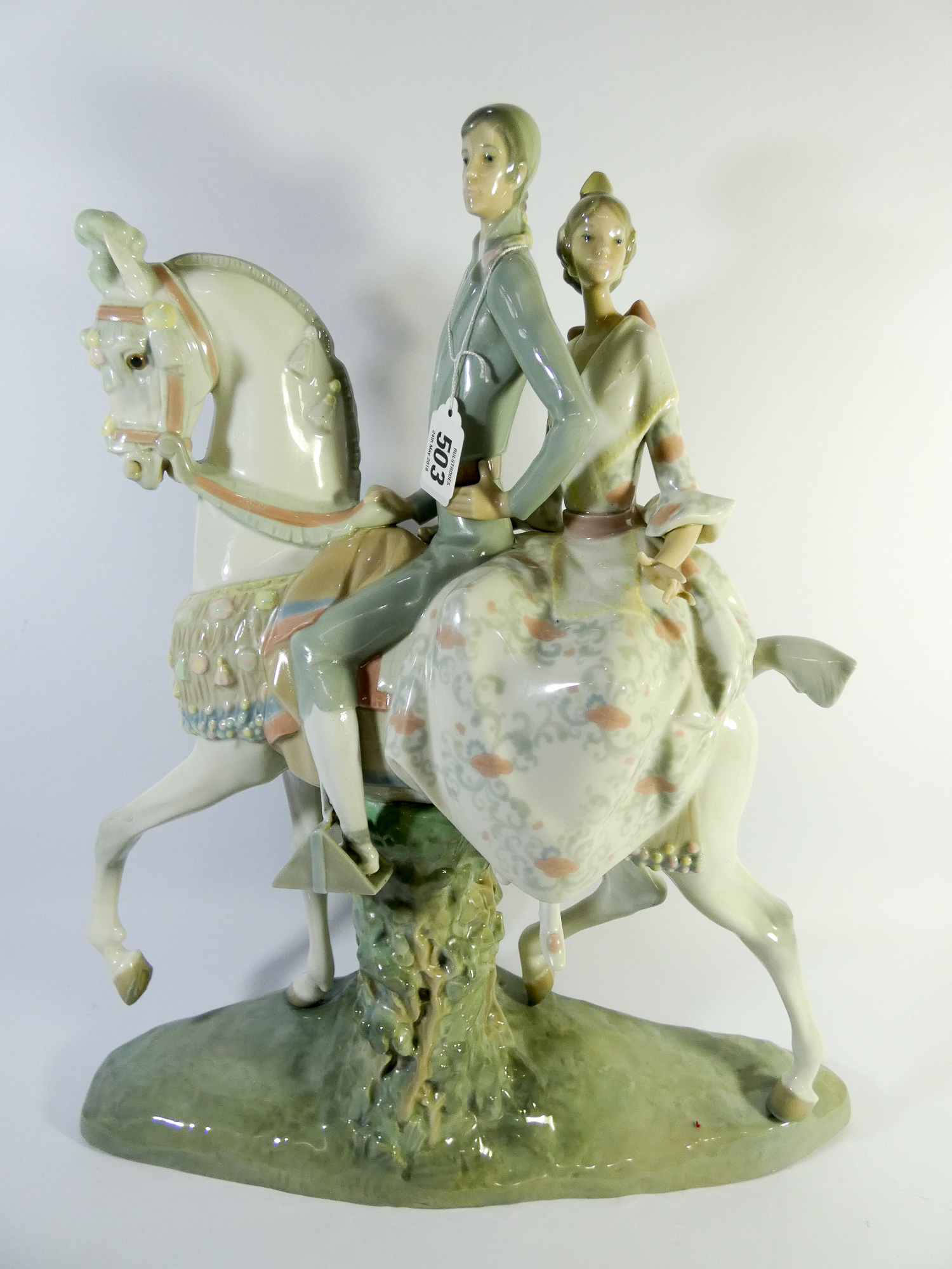 A large Lladro figure group fulgencio garcia of a couple astride a white station on a naturalistic