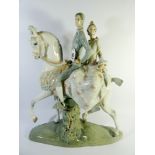 A large Lladro figure group fulgencio garcia of a couple astride a white station on a naturalistic