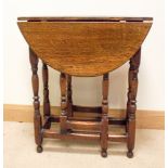 A late 19th early 20th century oval gate legged table on turned legs with cross stretchers,