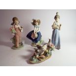 A collection of four Lladro porcelain figurines three girls holding bouquets and one of a kitten