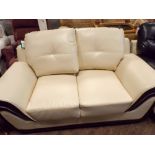 A new two seater settee in cream faux leather with black piping