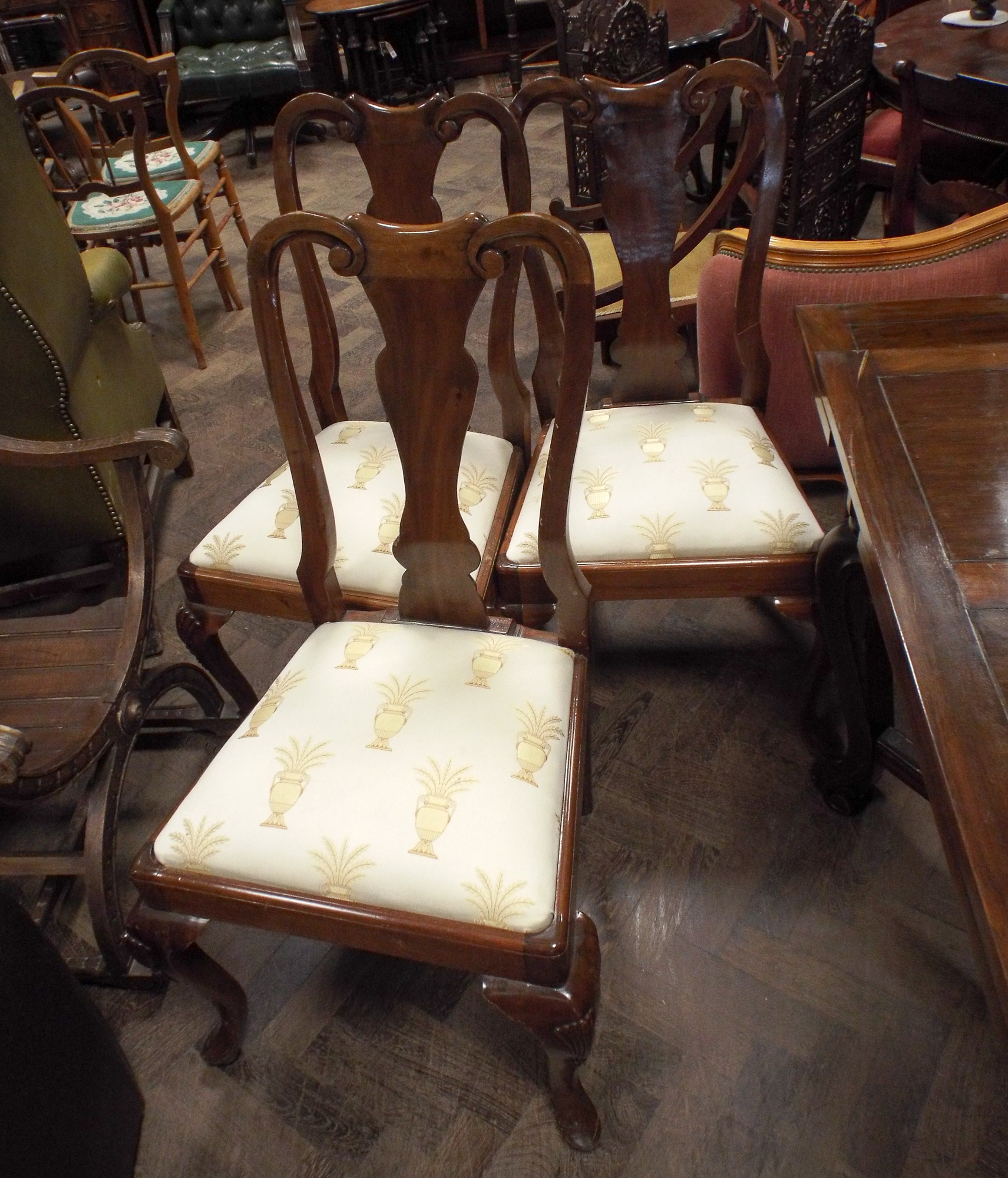 A set of eight Queen Anne style mahogany dining room chairs standing on cabriole legs with cream