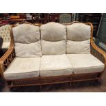 A bamboo framed conservatory three seater settee with loose cream cushions