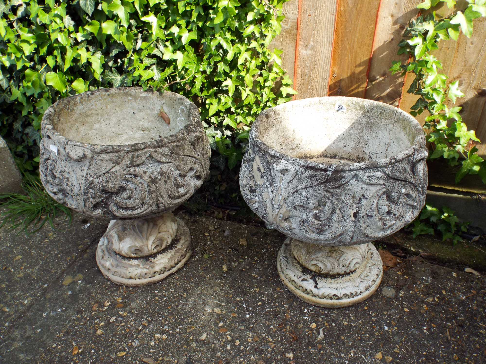 Two circular garden reconstituted stone planters on base, one as found,