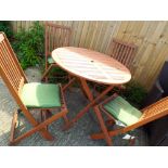 A circular folding wooden garden table and four matching folding chairs