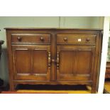 An Ercol dark oak sideboard fitted two cupboards and two drawers,