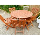 A hardwood folding circular garden table with six matching folding chairs