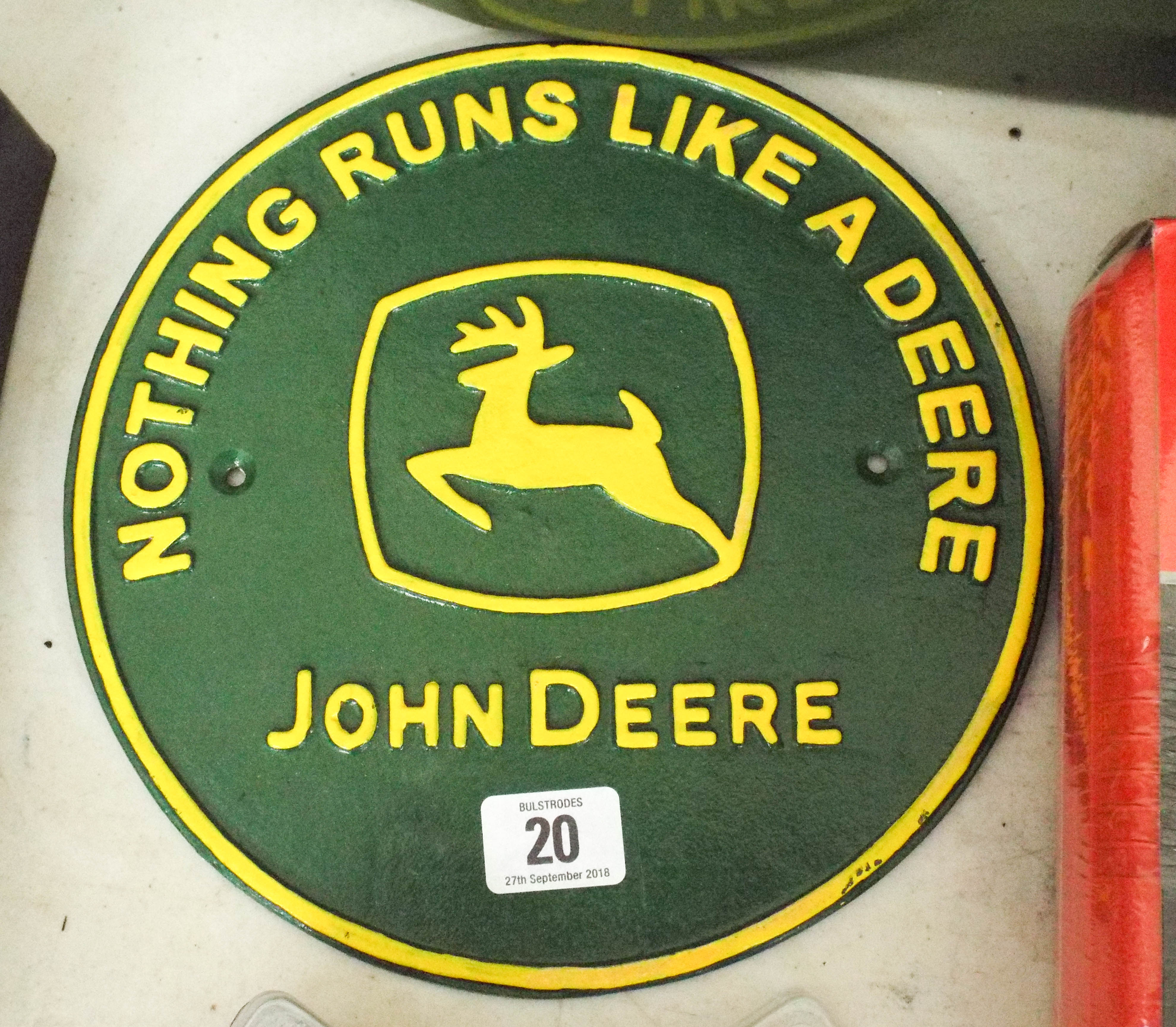 A circular John Deere advertising iron sign