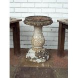 A reconstituted stone bird bath