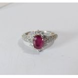 A 14ct white gold ruby and diamond cluster ring set with an oval ruby surrounded by brilliant cut