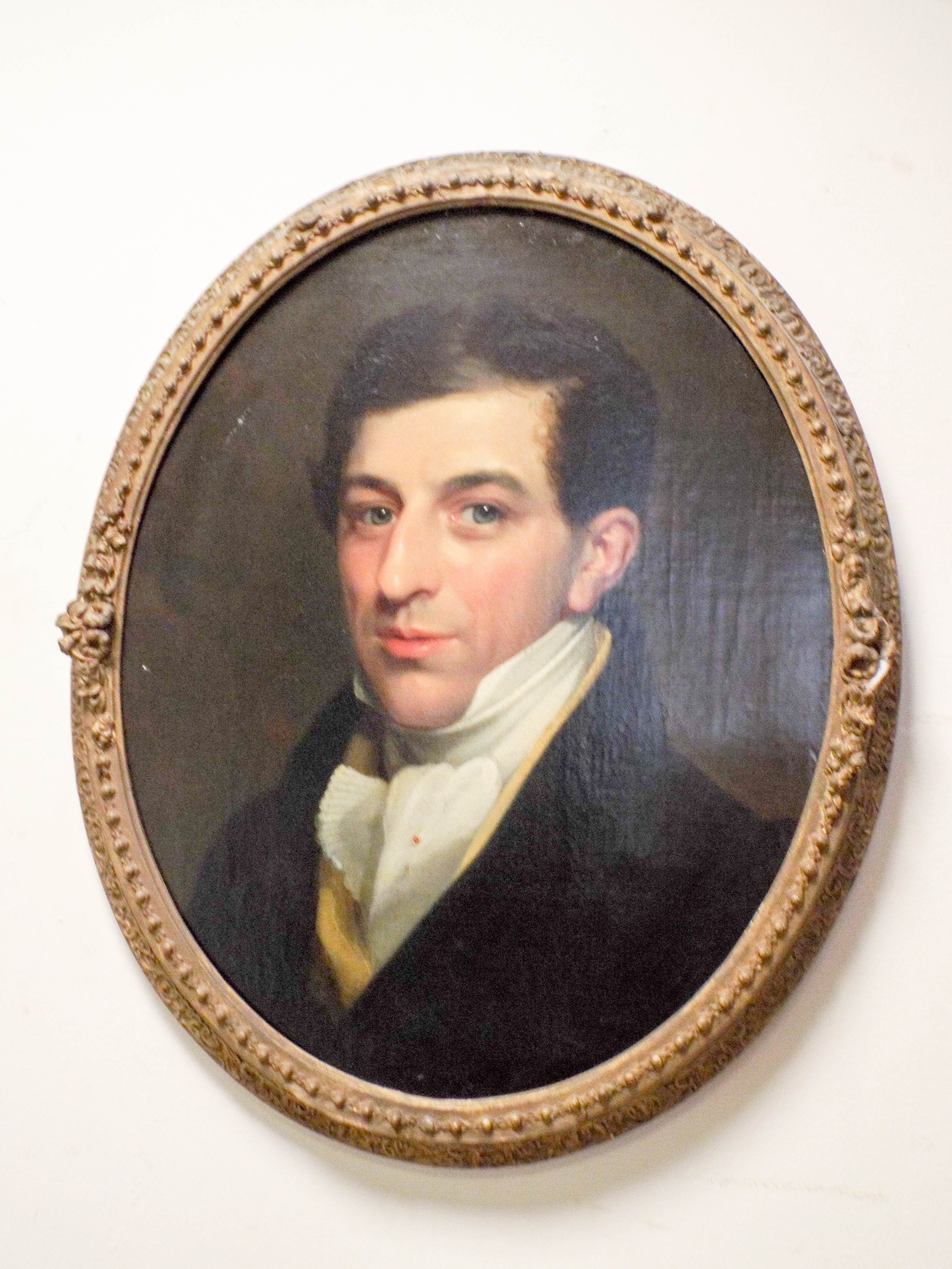 An early 19th Century oil on canvas portrait of a Regency gentleman in an oval gilt frame