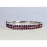 Modern 18ct white gold ladies hinged bangle set with a double row of rubies of good colour,