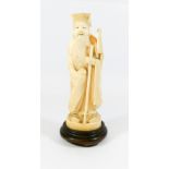 A Meiji period carved ivory figurine of a sage holding a staff mounted on a hardwood base,