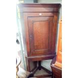 An antique oak corner cupboard on wooden stand