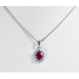 An 18ct white gold ruby and diamond cluster pendent set with a central oval ruby surrounded by 12