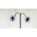 A pair of 18ct white gold mounted cluster earrings each set with a dark blue oval sapphire