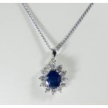 An 18ct white gold sapphire and diamond cluster pendent set with an oval sapphire surrounded by 12