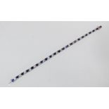 An 18ct white gold sapphire and diamond line bracelet set with 22 circular sapphires and 21