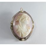 Oval carved angel coral cameo brooch, the decorative gold frame set with pearls, stamped 10K,
