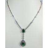 A 14ct white gold emerald and diamond necklace set with an oval emerald weighing 0.