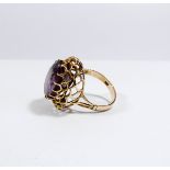 An amethyst statement dress ring set with a large oval mixed cut amethyst in a claw cage setting on