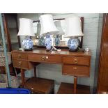 A GPlan mahogany kneehole dressing table and a pair of matching single drawer bedside tables