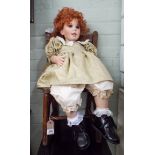 Large dressed doll seated in a wooden chair