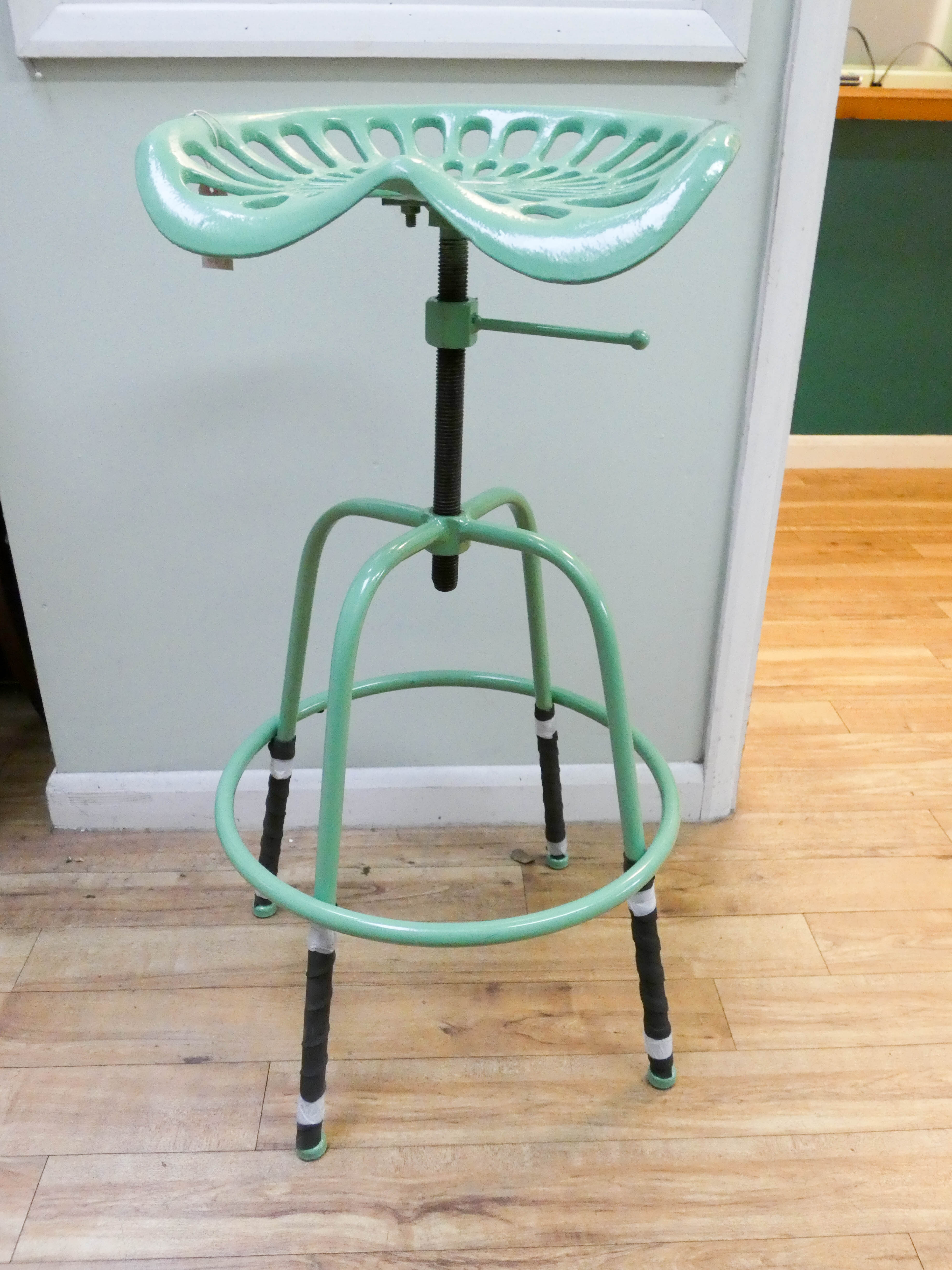 A green adjustable tractor stool