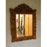 A Victorian carved medium oak cushioned style mirror with bevelled glass,