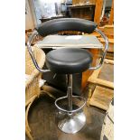 A high chrome framed adjustable swivel bar stool in black vinyl